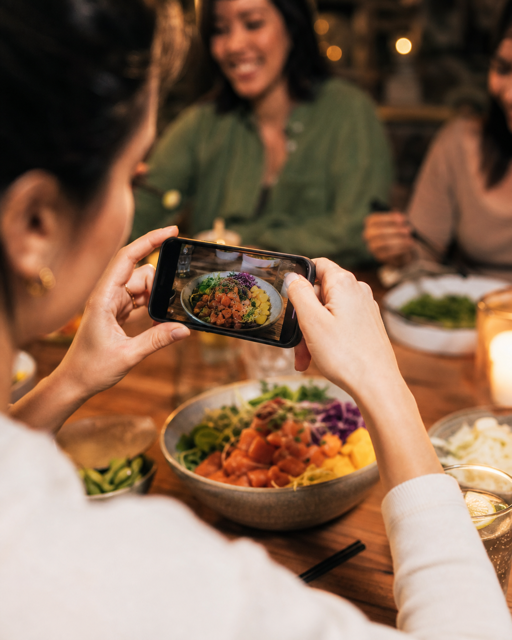 A person quickly photographing their meal with friends nearby